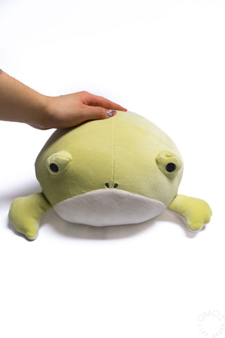 Small plush frog hugging pillow held in hand, lime-green body with white belly
