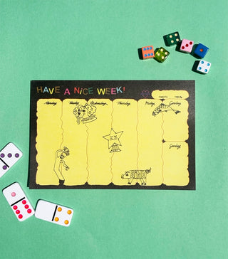 Desk planner with yellow weekly schedule blocks and 'Have a Nice Week!' text