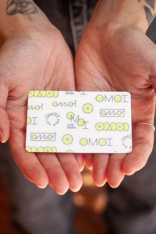OMOI gift card with playful pattern and OMOI logo, held in two hands