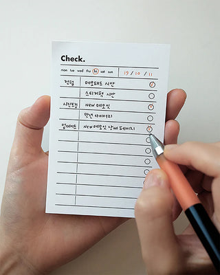 Memo pad with 'Check.' list, held in hands; pen points to circle checkbox
