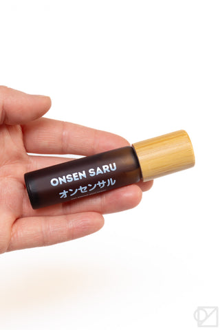Onsen Saru hot spring skin scent bottle with bamboo cap held in hand