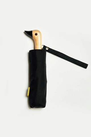 Black compact duckhead umbrella with wooden duck handle, folded in fabric sleeve