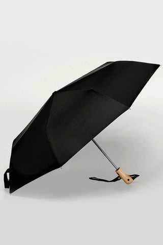Black compact duck umbrella open at an angle, wooden duck handle visible