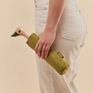 Olive compact duck umbrella folded in hand with duck-head handle