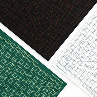 Stacked A4 cutting mats showing black, green, and white corners with measurement lines.