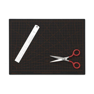 Black A4 cutting mat with grid; ruler and red-handled scissors placed on top.