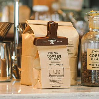 Brown plastic binder clip securing a paper bag and label