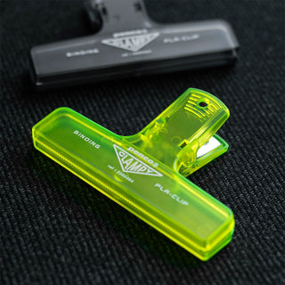 Transparent lime plastic binder clip on dark fabric