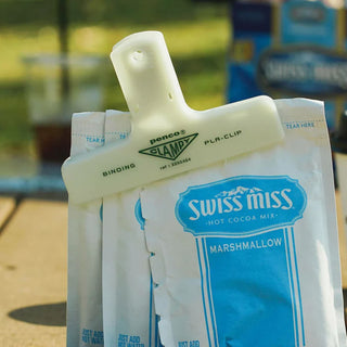 Cream plastic binder clip securing hot cocoa mix packets