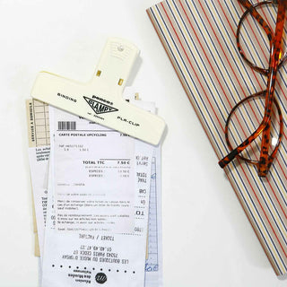 Plastic binder clip, cream white, holding stacked papers