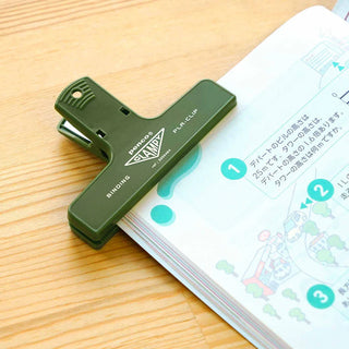 Dark green plastic binder clip labeled PENCO Clampy PLA-clip on paper stack
