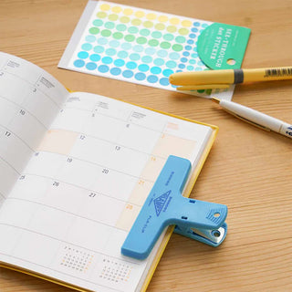Plastic binder clip, blue, clipped to open planner page