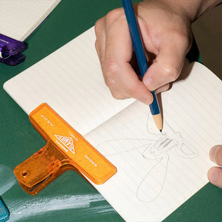 Plastic glitter binder clip, blue clamp held by hand with orange clip nearby