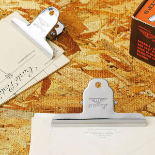 Silver and gold binder clips on papers with engraved logos