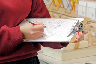 Blue clipboard with gold clip being used for writing