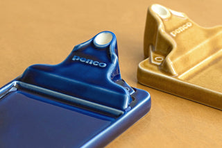 Navy ceramic incense holder tray with logo detail, shown beside a gold holder.