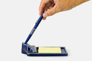 Navy incense holder tray with incense stick resting in the top ring; hand shown.