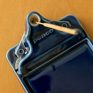 Close-up of navy ceramic incense holder base with ring opening and logo imprint.