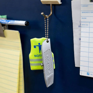Green pocket utility knife with keychain lanyard hanging beside office items