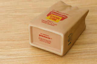 Close-up of PENCO brown paper bag pen holder with bottom label on a wood surface