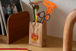 PENCO brown paper bag pen holder on desk with scissors, pens, and ruler