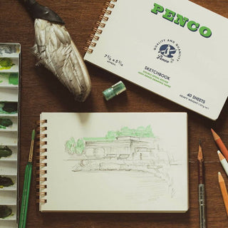 Heavy sketchbook with spiral spine and blank sketch page, drawing tools nearby