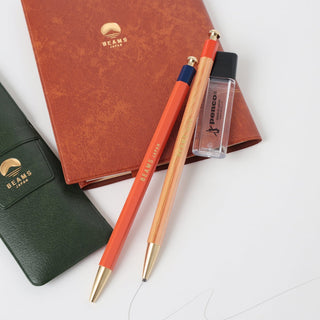 Orange mechanical pencil with natural wood barrel and pointed metal tip, with protective case