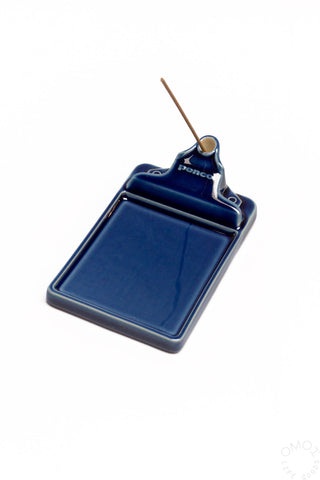 Navy ceramic incense holder tray with incense stick inserted through the top ring.