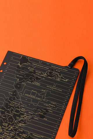 A5 notebook with world-map diagram print and black wrist strap, angled close-up