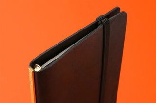 Black Bible-size notebook with elastic strap and thin side spine, chart-cover design