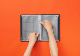 PLOTTER A5 fastener case open, hands insert papers into gray perforated grid binding