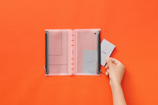 Bible-size fastener case opened, hand inserting cards into the pocket panels