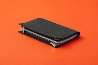 Black fastener case closed, with elastic bands and metal eyelets at the corners