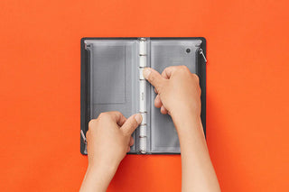 Narrow fastener case open with gray mesh pages and hands adjusting fasteners