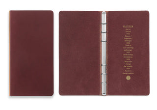 Narrow leather binder open with silver rings and red-brown interior pages