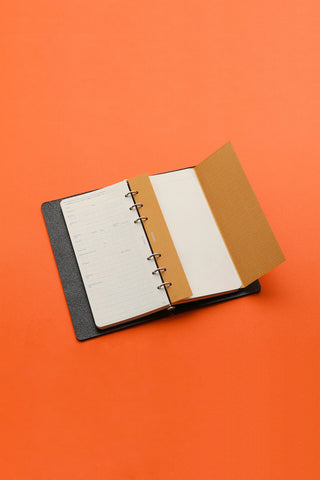 Narrow notebook with open pages, spiral binding, and kraft-style cover