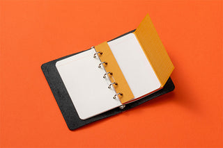 Open green leather mini binder with silver rings and two blank pages inside
