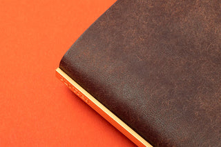 Brown leather mini binder cover corner close-up with cream page edge