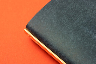 Navy leather binder spine with gold-toned edge trim, close-up