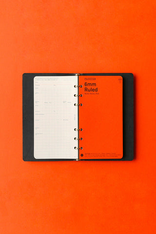 Black leather 6-ring binder open, showing 6 mm ruled pages