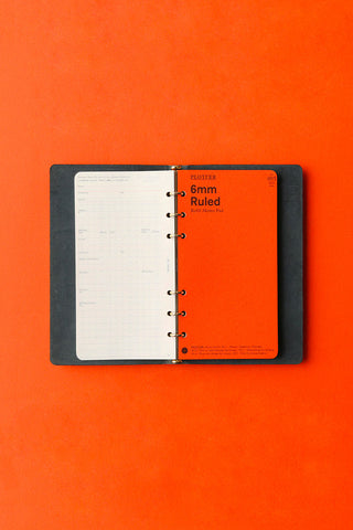 Open navy leather 6-ring binder with lined pages and orange insert