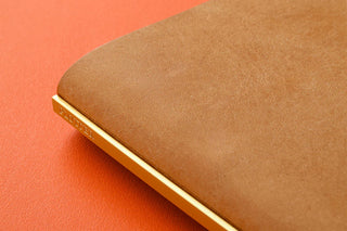 Beige leather binder edge close-up with gold-toned spine trim