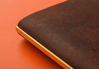 Brown leather binder with metal edges and spine detail on the narrow cover