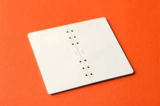 White 2mm grid memo pad pages with punched holes and black spine binding, closed