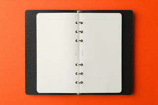 Black memo pad with 2mm grid pages, rings on spine, open flat