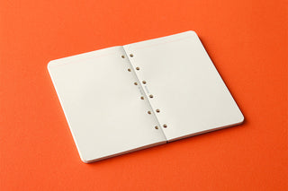 Mini refill memo pad with punched spine holes stacked on a flat surface