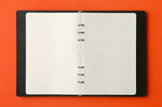Memo pad refill opened inside a dark cover; white ruled pages with center binder rings