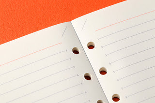 Close-up of 6mm ruled memo pad pages with red lines and circular punch holes