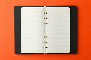 Open memo pad refill inside black cover with metal rings and ruled white pages