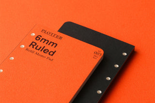 Two PLOTTER 6mm ruled memo pad refills stacked, orange and black covers